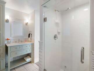 This elegant bathroom features a light blue vanity with marble countertops, complemented by a tiled backsplash and a matching medicine cabinet.