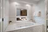 Indulge in relaxation in this luxurious bathroom, featuring a deep soaking tub surrounded by elegant white subway tile and marble accents.