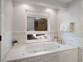 Indulge in relaxation in this luxurious bathroom, featuring a deep soaking tub surrounded by elegant white subway tile and marble accents.