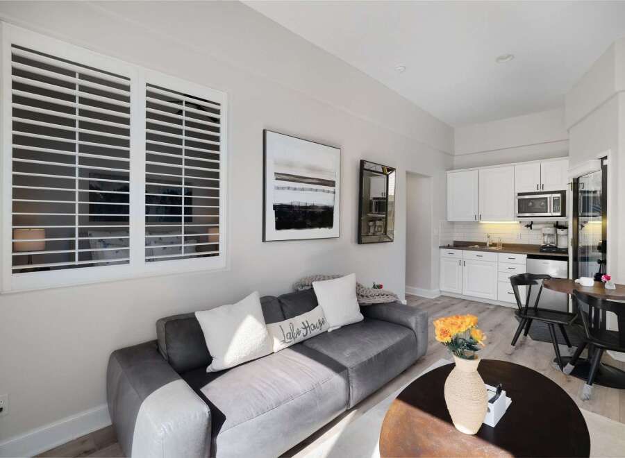 Experience comfortable living in this stylish studio apartment, featuring a plush gray sofa adorned with decorative pillows, including one that reads 'Lake House.