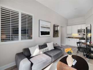 Experience comfortable living in this stylish studio apartment, featuring a plush gray sofa adorned with decorative pillows, including one that reads 'Lake House.