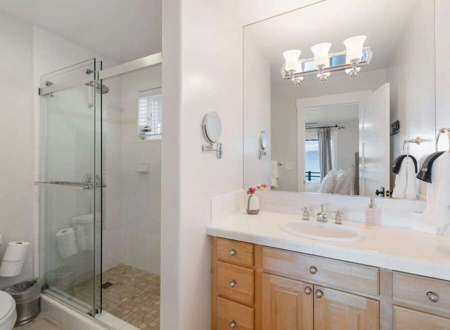 This bright and airy bathroom features a spacious glass-enclosed shower with white tiled walls and a tiled floor.