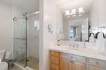 This bright and airy bathroom features a spacious glass-enclosed shower with white tiled walls and a tiled floor.