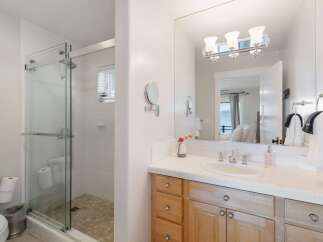 This bright and airy bathroom features a spacious glass-enclosed shower with white tiled walls and a tiled floor.