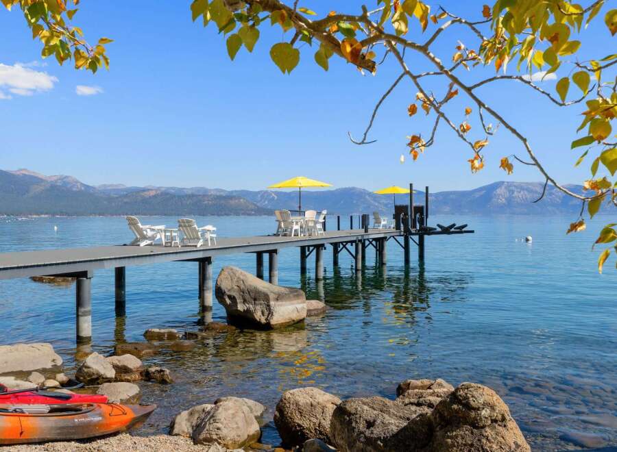 Enjoy breathtaking lake views from this stunning property featuring a private dock with seating and umbrellas, perfect for relaxing or entertaining.