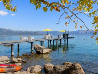 Enjoy breathtaking lake views from this stunning property featuring a private dock with seating and umbrellas, perfect for relaxing or entertaining.