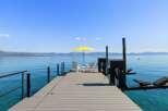 Enjoy breathtaking lake views from this stunning property featuring a private dock with seating and a vibrant yellow umbrella.