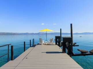 Enjoy breathtaking lake views from this stunning property featuring a private dock with seating and a vibrant yellow umbrella.