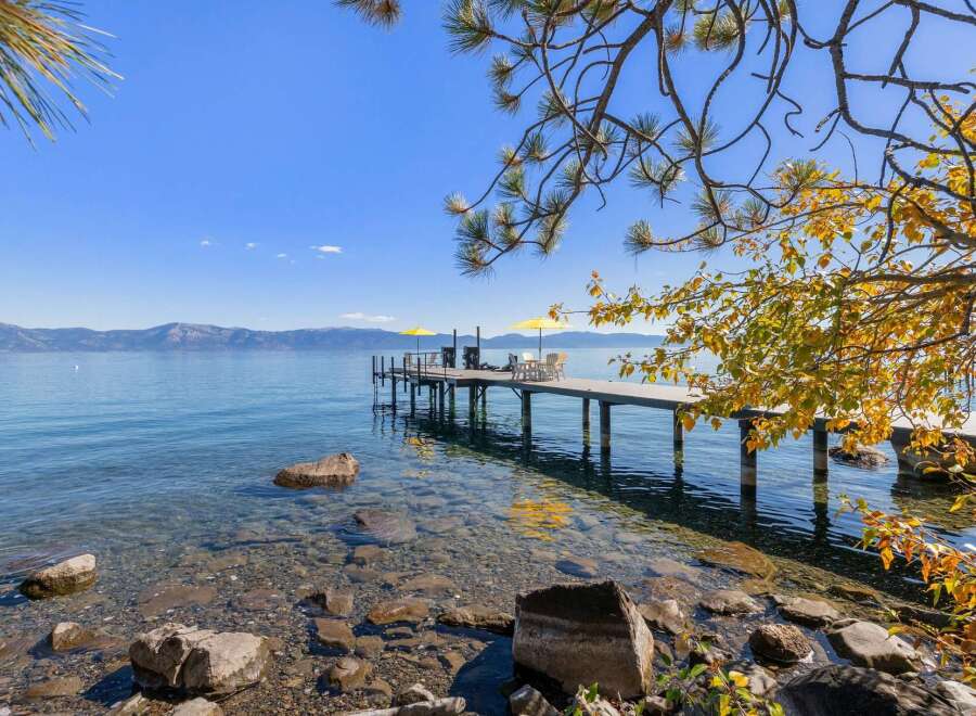 Enjoy breathtaking lake views from this stunning property featuring a private dock with seating and umbrellas, perfect for relaxing by the water.
