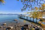 Enjoy breathtaking lake views from this stunning property featuring a private dock with seating and umbrellas, perfect for relaxing by the water.