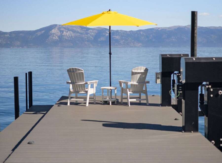 Enjoy breathtaking lake views from this serene dock, complete with two Adirondack chairs and a bright yellow umbrella for ultimate relaxation.