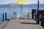 Enjoy breathtaking lake views from this serene dock, complete with two Adirondack chairs and a bright yellow umbrella for ultimate relaxation.