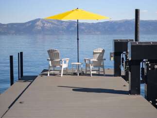 Enjoy breathtaking lake views from this serene dock, complete with two Adirondack chairs and a bright yellow umbrella for ultimate relaxation.