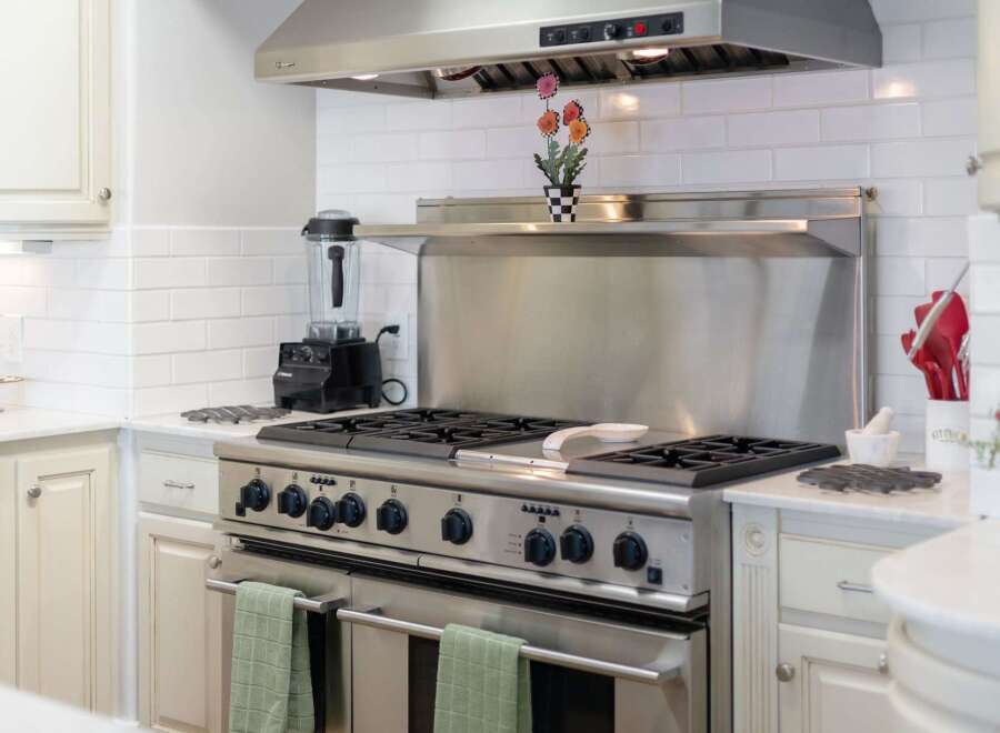 This modern kitchen boasts a professional-grade stainless steel range with a powerful exhaust hood, perfect for any culinary enthusiast.