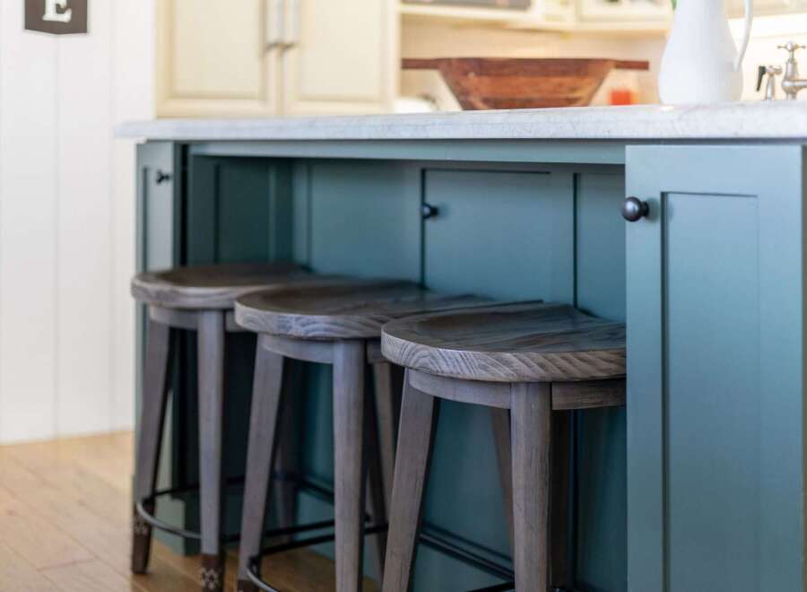 This kitchen island features a stunning teal painted finish, complemented by a durable concrete countertop.