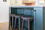 This kitchen island features a stunning teal painted finish, complemented by a durable concrete countertop.