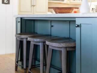 This kitchen island features a stunning teal painted finish, complemented by a durable concrete countertop.