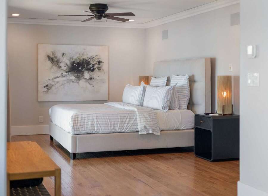 Experience modern comfort in this elegantly appointed bedroom, featuring a plush king-sized bed with crisp, striped linens and a sophisticated upholstered headboard.