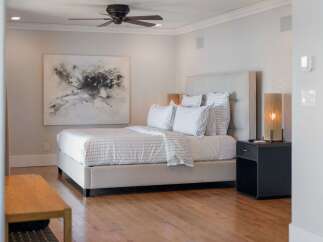 Experience modern comfort in this elegantly appointed bedroom, featuring a plush king-sized bed with crisp, striped linens and a sophisticated upholstered headboard.