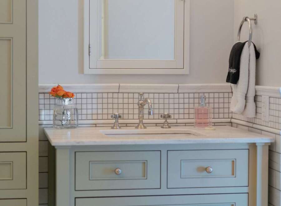 This elegant bathroom vanity features a marble countertop and a light blue cabinet with decorative knobs.