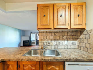Discover this charming kitchen featuring a double stainless steel sink and a speckled countertop, perfect for meal preparation.