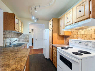 This kitchen features warm oak cabinetry and a classic tiled backsplash, offering a timeless aesthetic.