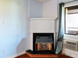 Cozy up by the corner fireplace, featuring a classic white mantel and a black insert with wooden accents.