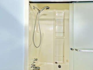 Step into a clean and functional bathroom featuring a classic cream-colored bathtub and shower unit.