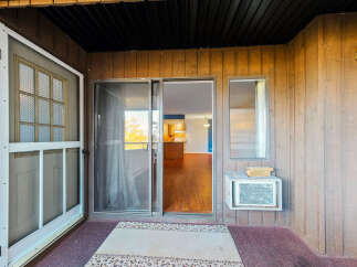 Step into this inviting space featuring a sliding glass door that opens to a well-lit interior with hardwood floors.