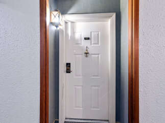 Step into this charming apartment, featuring a classic white door with a decorative knocker and the unit number '303' clearly displayed.
