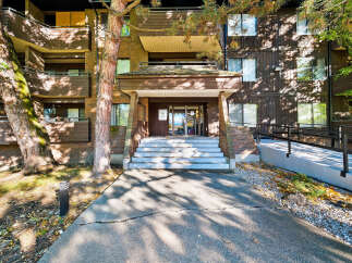 Discover this charming apartment building featuring a welcoming entrance with a covered walkway and a set of stairs leading to the main doors.