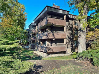 Discover this charming multi-story apartment building, featuring a modern facade with brown horizontal siding and balconies on each level.