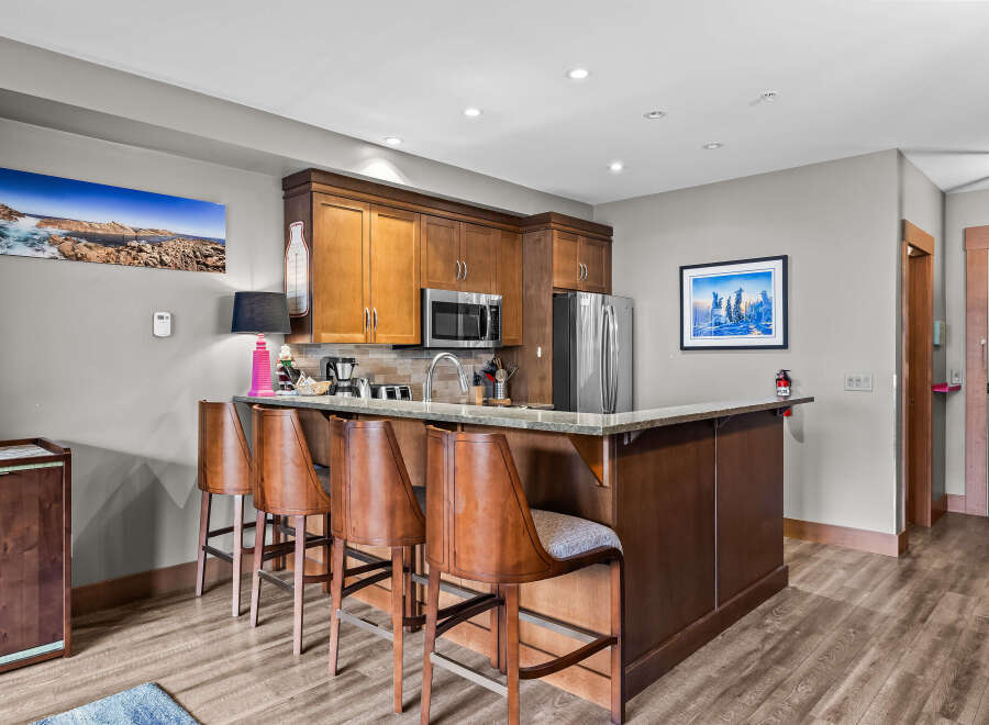 Experience modern living in this beautifully appointed kitchen, featuring rich wood cabinetry, a sleek granite countertop, and a convenient breakfast bar with comfortable seating.