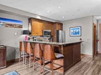 Experience modern living in this beautifully appointed kitchen, featuring rich wood cabinetry, a sleek granite countertop, and a convenient breakfast bar with comfortable seating.