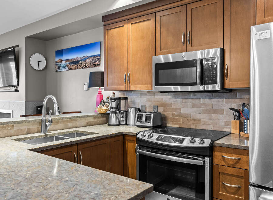 This modern kitchen boasts sleek stainless steel appliances, including a microwave, refrigerator, and oven, complemented by warm wooden cabinetry.
