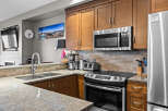 This modern kitchen boasts sleek stainless steel appliances, including a microwave, refrigerator, and oven, complemented by warm wooden cabinetry.