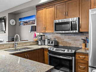 This modern kitchen boasts sleek stainless steel appliances, including a microwave, refrigerator, and oven, complemented by warm wooden cabinetry.