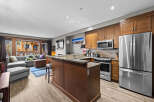 This open-concept living space features a modern kitchen with stainless steel appliances, granite countertops, and ample wooden cabinetry.