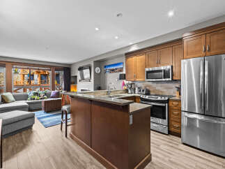 This open-concept living space features a modern kitchen with stainless steel appliances, granite countertops, and ample wooden cabinetry.