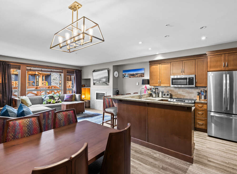 Experience luxury living in this stunning open-concept space, featuring a modern kitchen with stainless steel appliances and a breakfast bar, seamlessly flowing into a comfortable living area with a fireplace.