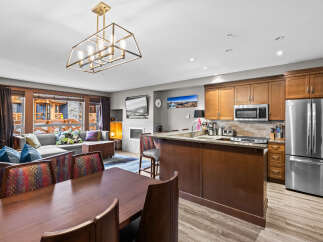Experience luxury living in this stunning open-concept space, featuring a modern kitchen with stainless steel appliances and a breakfast bar, seamlessly flowing into a comfortable living area with a fireplace.