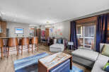 Experience luxury living in this stunning open-concept condo, featuring a modern kitchen with a breakfast bar and sleek stainless steel appliances.