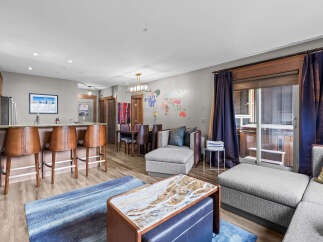 Experience luxury living in this stunning open-concept condo, featuring a modern kitchen with a breakfast bar and sleek stainless steel appliances.