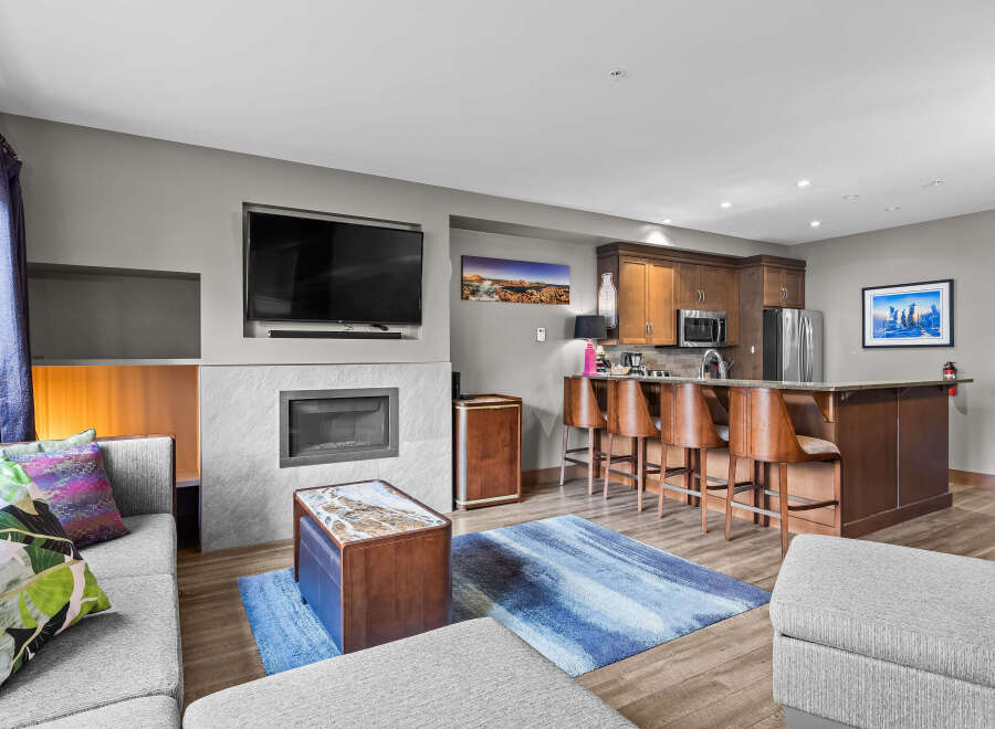 Experience modern living in this stylish open-concept condo, featuring a sleek fireplace and a large flat-screen TV for cozy evenings.