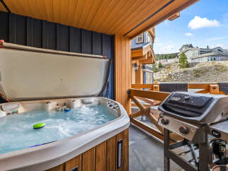 Enjoy ultimate relaxation and entertainment on this private balcony, featuring a bubbling hot tub perfect for unwinding after a day on the slopes.