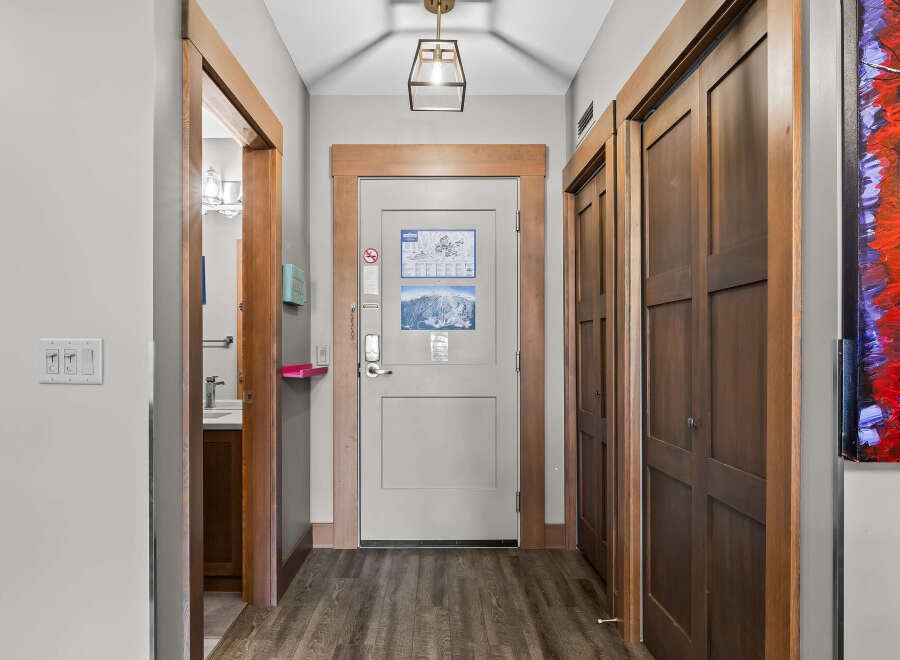 Step into this inviting hallway, featuring a modern light fixture and warm wood accents.
