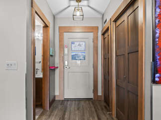 Step into this inviting hallway, featuring a modern light fixture and warm wood accents.