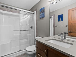 This modern bathroom features a sleek white shower stall with glass doors, complemented by a minimalist toilet and a floating vanity with a concrete countertop.