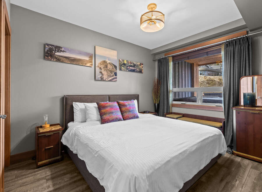 Experience comfort and style in this inviting bedroom, featuring a plush king-sized bed adorned with decorative pillows and crisp white linens.