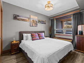 Experience comfort and style in this inviting bedroom, featuring a plush king-sized bed adorned with decorative pillows and crisp white linens.